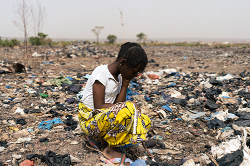 girl in garbage heap chil labor - log